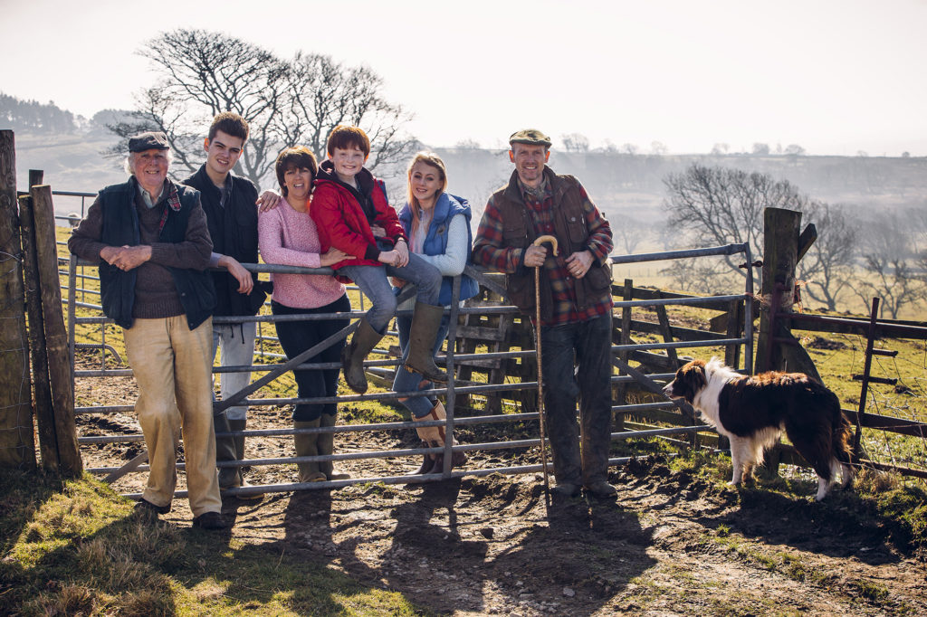 Family generation standing at farm gate